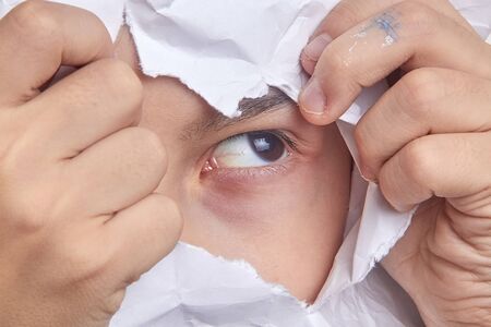 Spy Little boy looking through paper. Spy eye watching through a hole.の写真素材