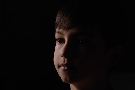 portrait of a boy on a dark background close up face.の写真素材