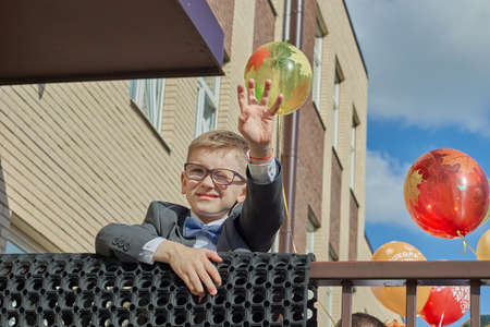 Russia, Saint-Petersburg, September 2019: a boy with glasses waves his hand against the background of balloons back to school.のeditorial素材