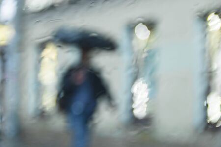 It 's raining hard, through the window. Blurred silhouettes of people in the city go about their business selevtive focusの写真素材