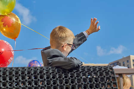 Russia, Saint-Petersburg, September 2019: a boy with glasses waves his hand against the background of balloons back to school.のeditorial素材