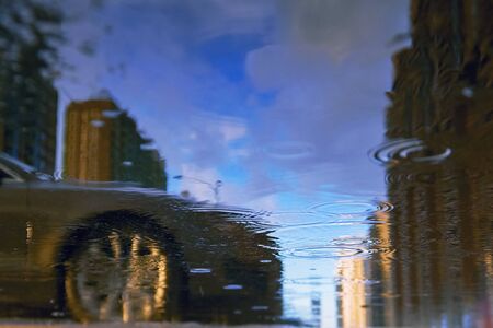 Drops of rain bubbling in a puddle with the reflection of light.の写真素材