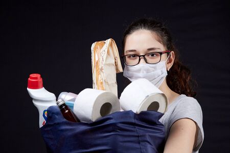 Young woman in protective mask with a bag full of groceries from the supermarketの写真素材