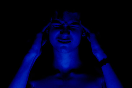 Portrait with a blue treatment of a teenager on a black background. Concept of pain and tension.の写真素材