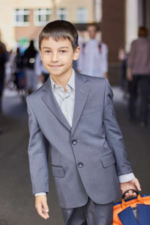back to school portrait of a young boy with a backpack and a business suit.の写真素材
