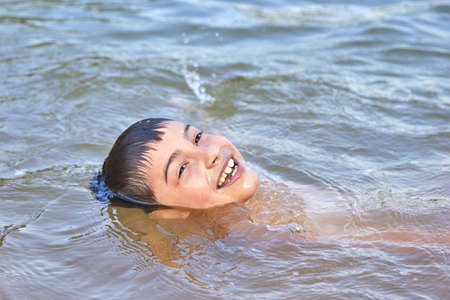 cute boy happily bathes in the water.の写真素材