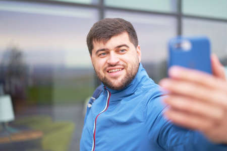 Portrait of bearded tourist man with backpack enjoy the beautiful view of the modern city, beautiful bearded man selfie in the cityの写真素材