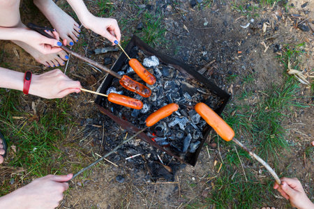 Picnic, barbecue, cooking food concept. Sausages roasted on bonfire flame . Summer camping, hiking, vacationの写真素材