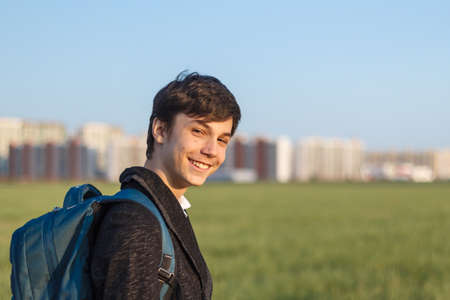 School teenager waiting for a school bus, on his way to school. On the way home from school against the background of the urban landscapeの写真素材