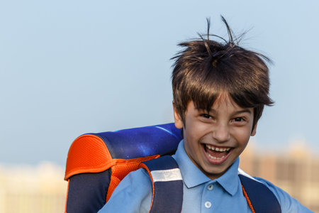 Portrait of happy boy with backpack, school child waiting for school bus, primary school student, on...
