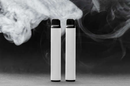 E-cigarettes on dark background in smoke, mocap, front viewの写真素材