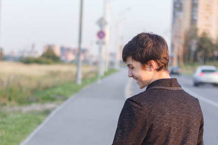 Portrait of a happy smiling teenager with a backpack, a school teenager waiting for a school bus, on...