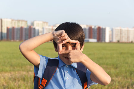 Portrait of happy boy with backpack, school child waiting for school bus, primary school student, on...
