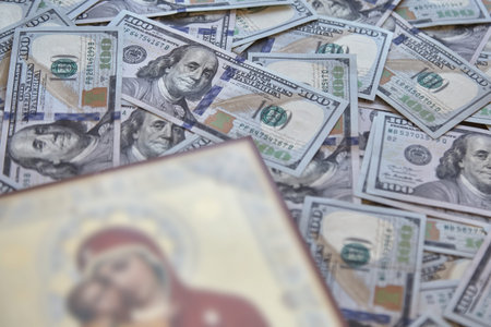 silhouette of a religious icon against a background of hundred-dollar bills, the concept of bribes