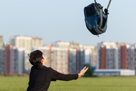 Teen dropped his backpack up after school, amid urban landscape.