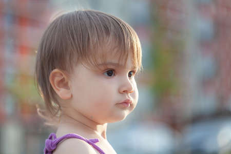Portrait of a two year old child against the background of the sunrise in the city.の写真素材