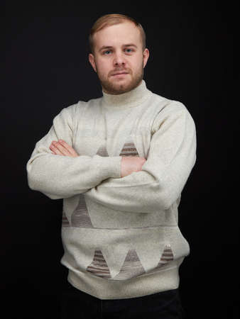 vertical portrait of a waist length blond man on a dark background, in a jacketの写真素材