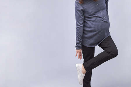 A pregnant young woman puts on her shoes.の写真素材