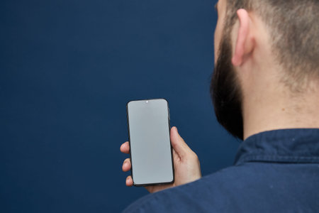men with a beard in a shirt back with a phone