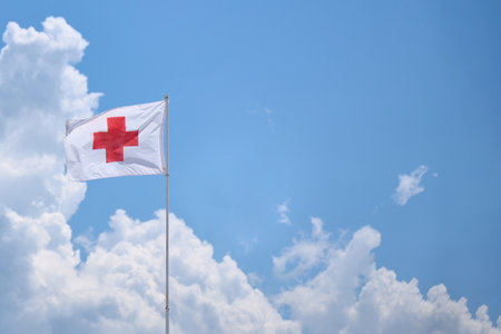 red cross rescue flag on a blue background with clouds.の写真素材