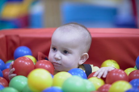 a one-year-old child, a boy, a joyful kid in toys, a lot of balls