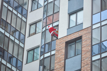 santa descends through the window of a multi-storey apartment building in order to give a gift to a...