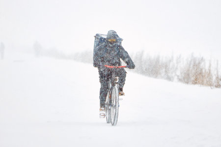Man Snow Biking Down a Slope During Winter Snowstormの写真素材