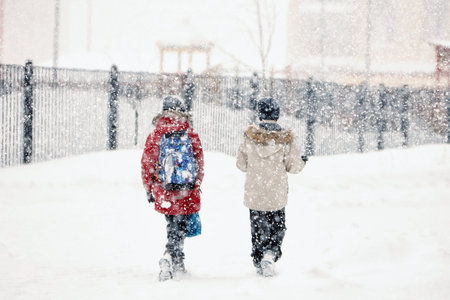 Two friends overcoming a winter snowstorm as they walk through the snow, in a snowfall