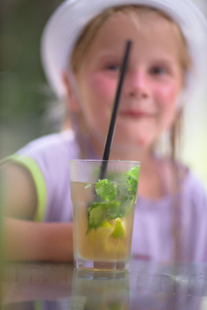 Refreshing green lemonade in a glass on the table against the background of nature. Freshly squeezed drinks with ice. Lemonade with lemon, mint lime and herbsの写真素材
