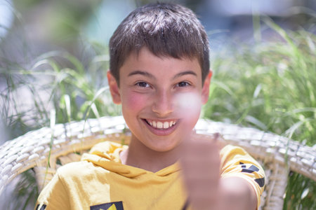 portrait of a child, burnt skin in the sun, a 10-year-old brunette boy in a summer cafe. Drinks a mojito and eats a hamburgerの写真素材