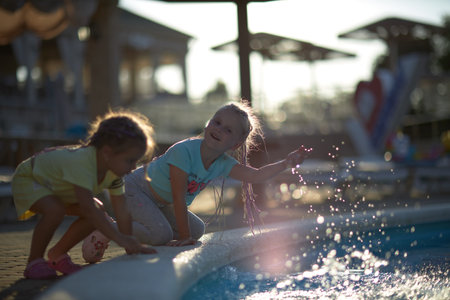 Two Little Girls Playing in a Pool With a Surfboardの写真素材