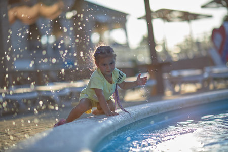 a four-year-old boy lies in a childrens inflatable pool, splashing water, smiling. Nearby float toys. View from above. High quality photoの写真素材