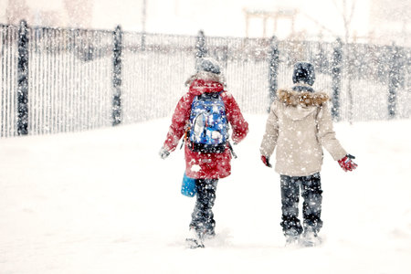 Two friends overcoming a winter snowstorm as they walk through the snow, in a snowfall