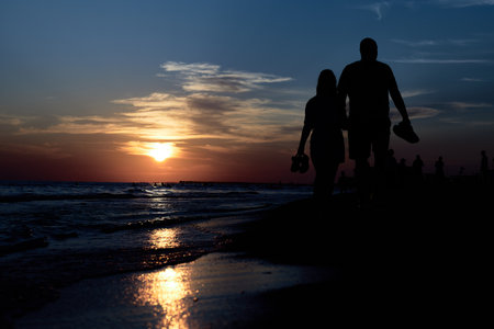 Silhouettes of Love: A Romantic Stroll Along the Sunset Beachの写真素材