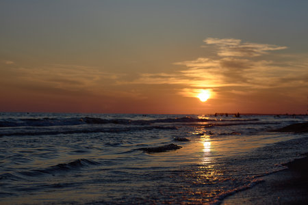 Serene Sunset Symphony: Sun Descending Over Beach Watersの写真素材