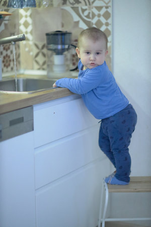 Little Boy Standing on Stool in Kitchenの写真素材