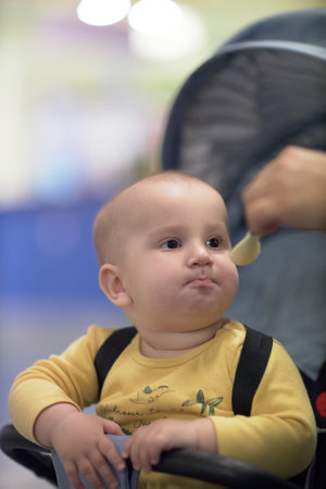 a one-year-old child, a boy, eats on the road, has a snack on the way in a strollerの写真素材