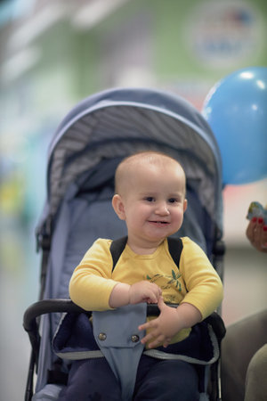 a one-year-old child, a boy, eats on the road, has a snack on the way in a strollerの写真素材
