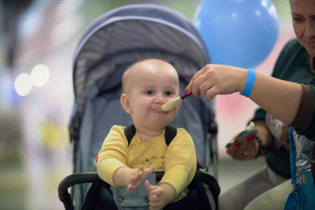 a one-year-old child, a boy, eats on the road, has a snack on the way in a strollerの写真素材