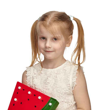 Blonde baby 6 years old, in a white dress shows watermelonの写真素材