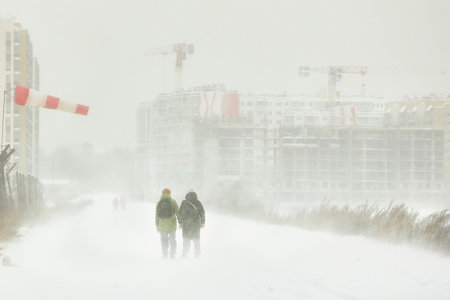 Two People Walking Down Snow-Covered Street During Winter Snowstormの写真素材