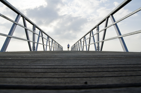 man walking away on a bridgeの写真素材