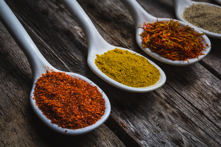 Powder spices on spoons in vintage wooden table backgroundの写真素材