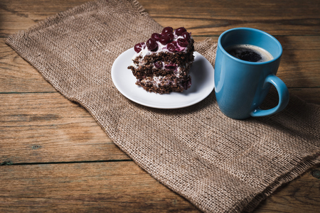 Cup of coffee and cherry cake on wooden backgroundの写真素材