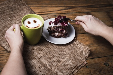 Cappuccino with smile and cherry cake on wooden backgroundの写真素材
