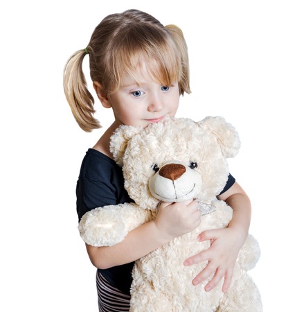 Little girl with teddy bear is looking at the camera isolated on white backgroundの写真素材