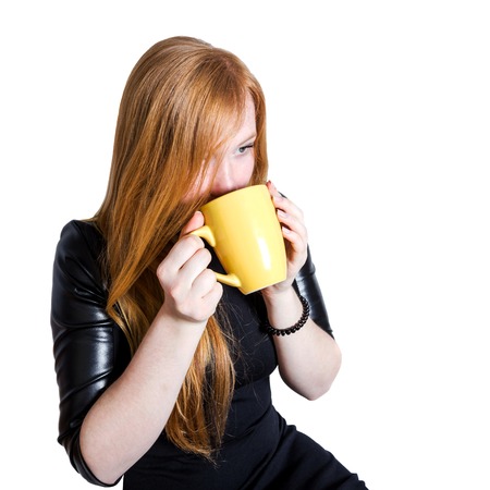 Girl with red hair with cup of tea isolated on white backgroundの写真素材