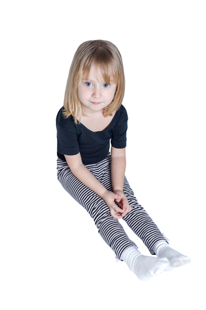 Lonely little girl sitting on the floor isolated on white backgroundの写真素材