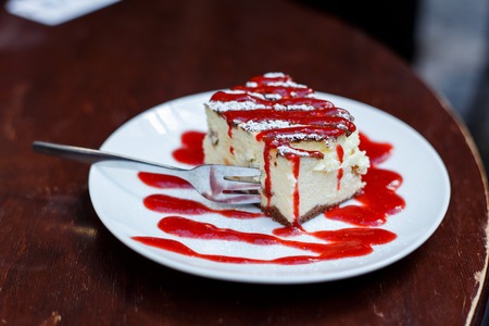 Tasty piece of cheesecake with berry sauce on plate on table close upの写真素材