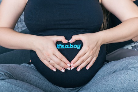 Beautiful pregnant woman holding a sign which says it's a boyの写真素材